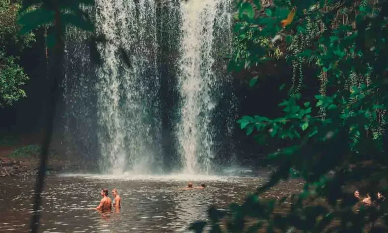 Pessoas se banhando na base de uma cachoeira rodeada por vegetação em uma área próxima a Salvador