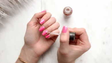 Mulher aplicando esmalte com brilho sobre unhas rosa em um momento de cuidado pessoal