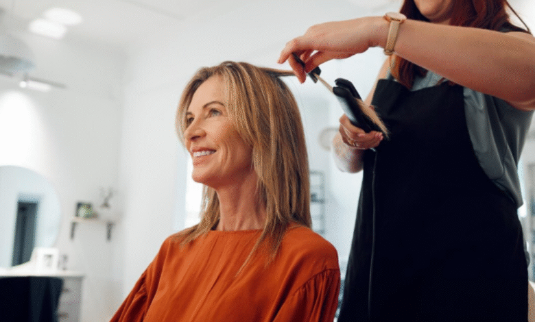 Mulher sorrindo enquanto recebe penteado no salão, corte Riviera Bob em destaque, simbolizando a tendência de cabelo em 2025.