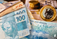 Dinheiro brasileiro em cédulas e moedas, representando benefícios previdenciários.