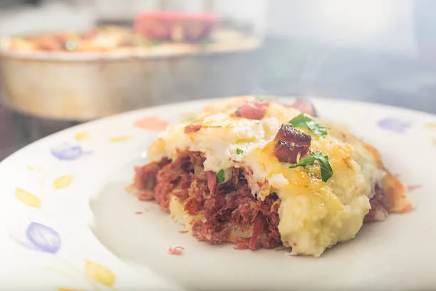 Porção de escondidinho de carne de sol com aipim, prato típico nordestino, servido com queijo derretido