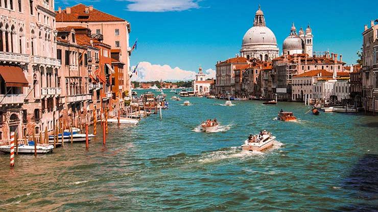 Canal em Veneza com barcos navegando e edifícios históricos ao redor
