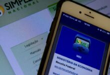 Smartphone com o aplicativo MEI aberto em primeiro plano e o site do Simples Nacional ao fundo.