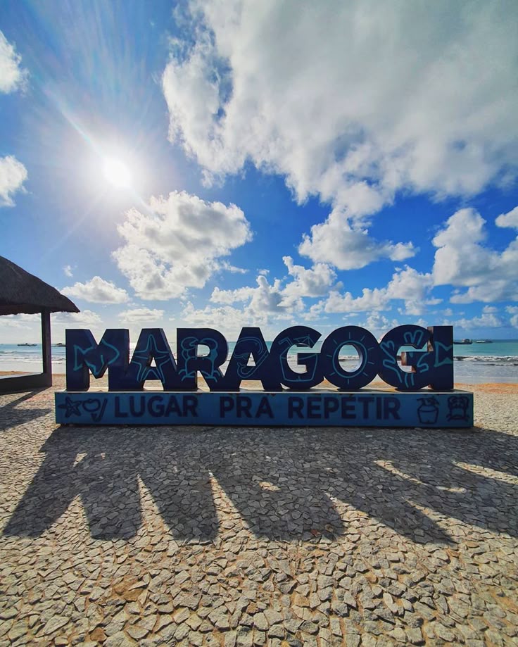 Placa turística de Maragogi com praia e céu azul ao fundo