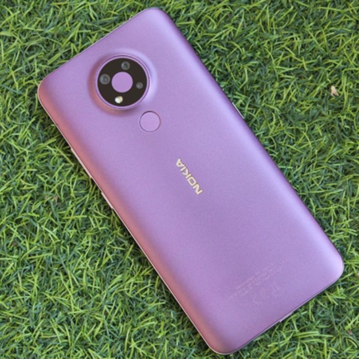 Smartphone Nokia G20 roxo, visto de costas sobre um gramado verde, destacando as câmeras circulares e o sensor de impressão digital.