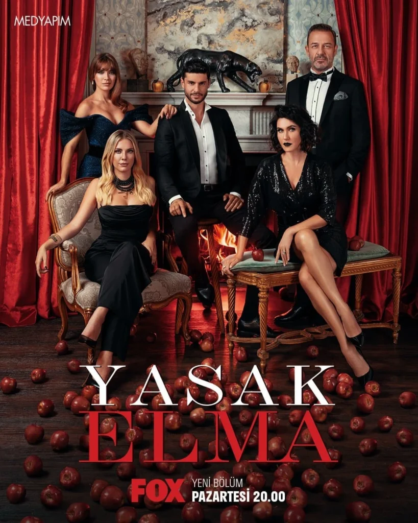 Elenco da novela turca O Fruto Proibido posando em ambiente elegante, cercados por maçãs vermelhas
