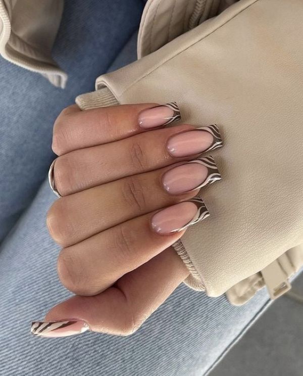 Unhas com esmaltação nude e francesinha com estampa zebrada no estilo manicure italian.