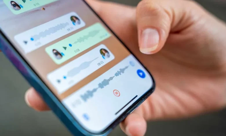 Pessoa segurando um smartphone com a tela do WhatsApp mostrando mensagens de voz
