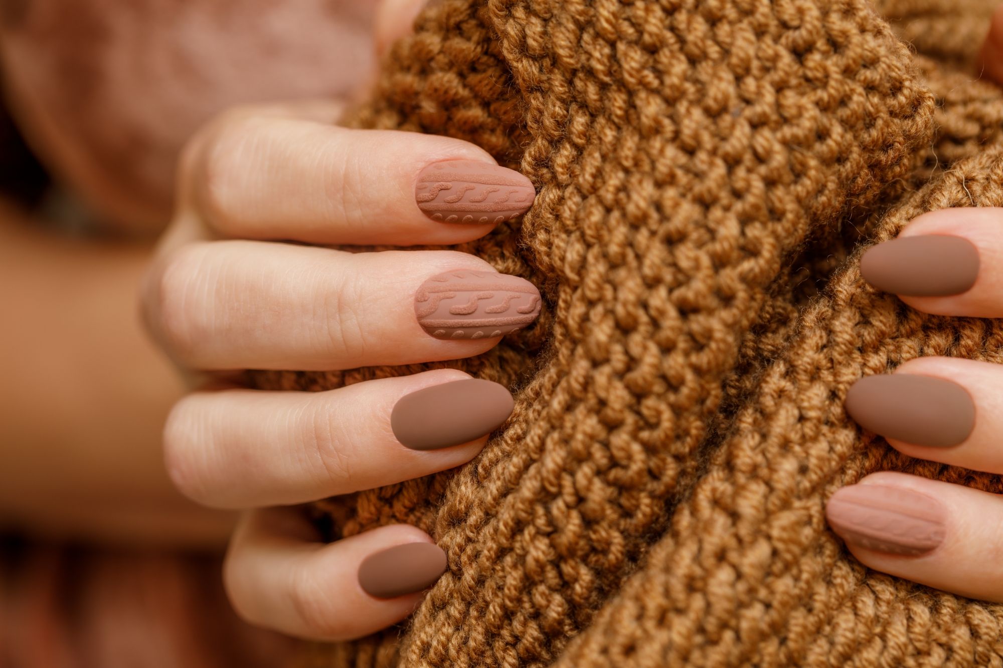 Unhas com textura 3D imitando tricô, em tom bege, criando um efeito aconchegante e sofisticado para o outono de 2025.