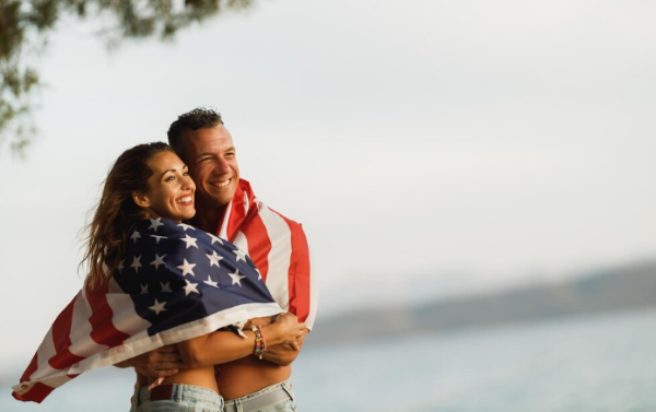 Casal feliz abraçado com uma bandeira dos Estados Unidos, simbolizando a conexão entre a documentação americana e a atualização no INSS.