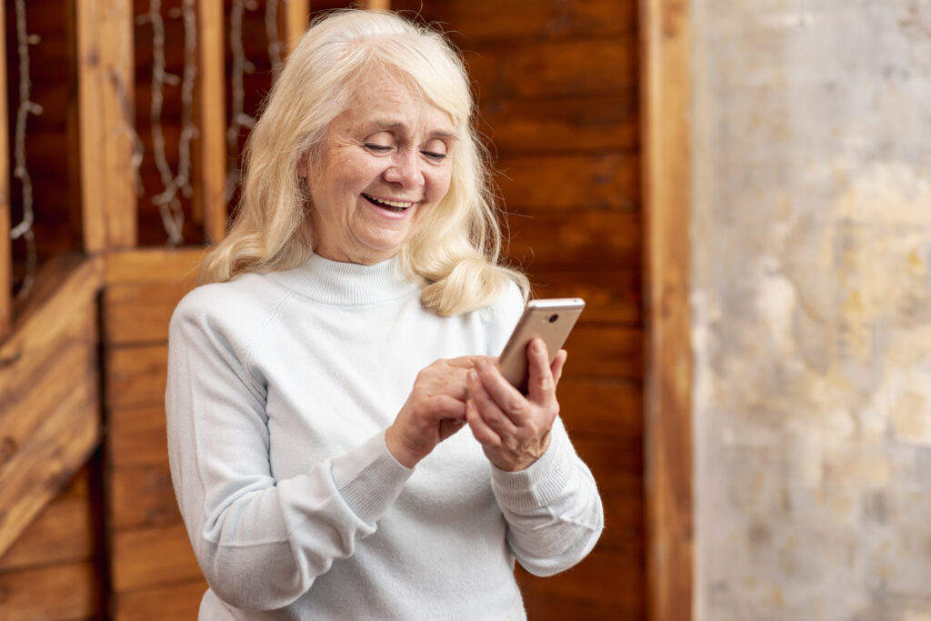 Idosa sorridente usando smartphone em ambiente aconchegante