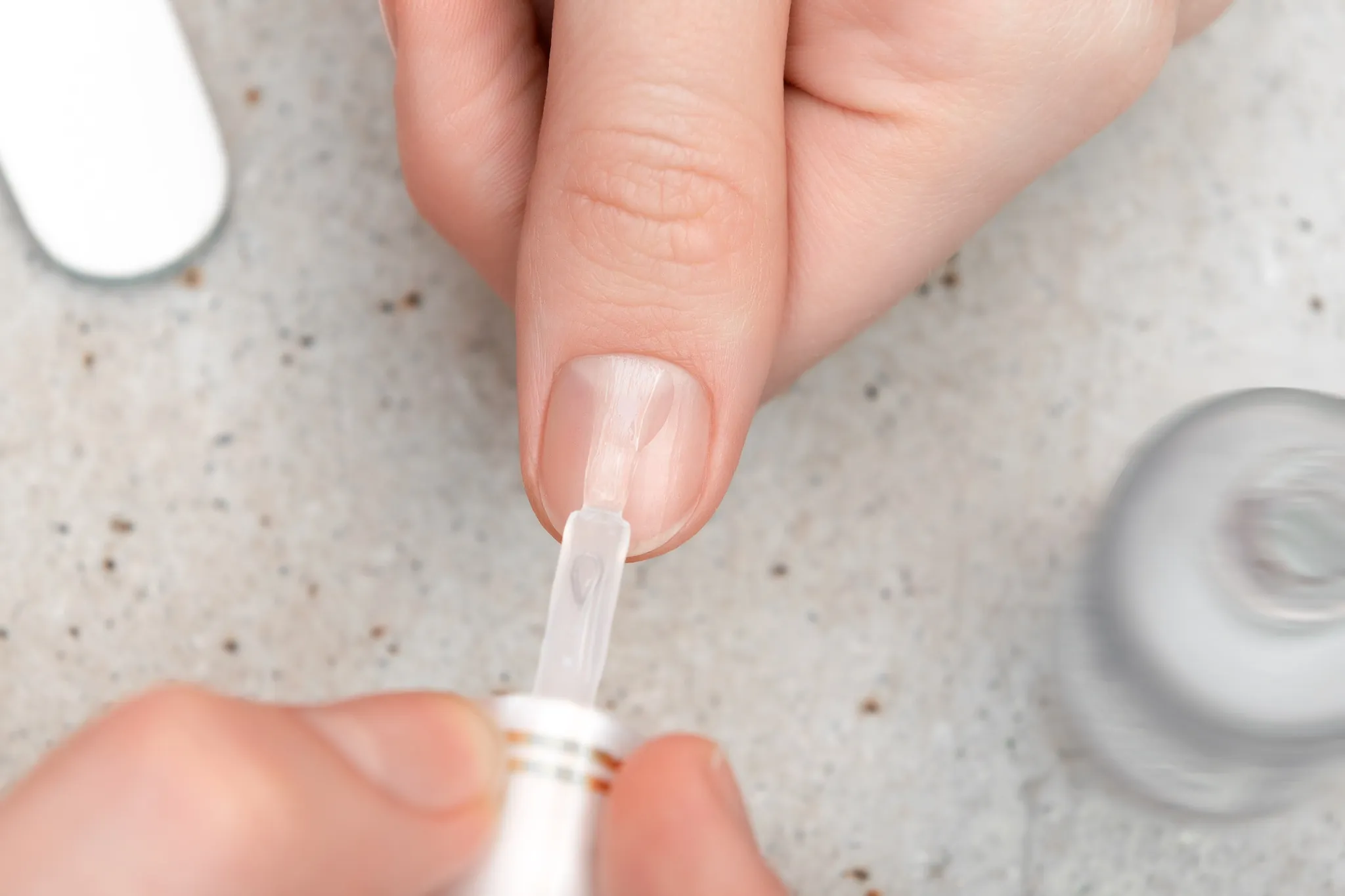 Aplicação de top coat transparente para finalizar a manicure.