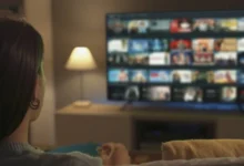 Mulher assiste a uma seleção de séries em uma plataforma de streaming na TV