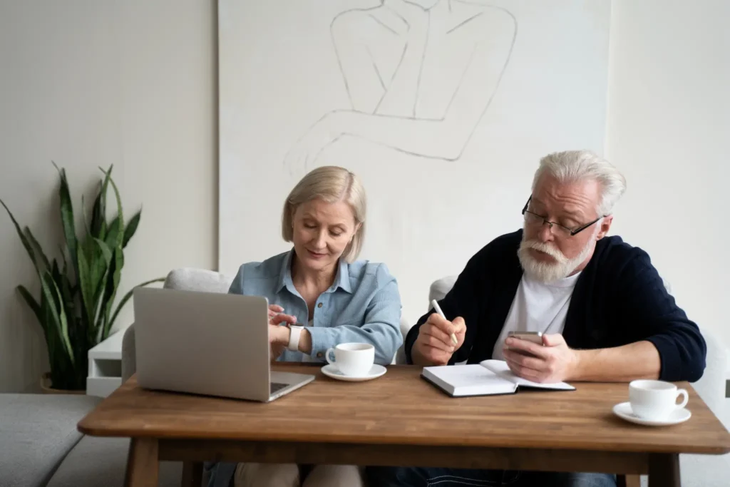 Casal de idosos analisando finanças com tecnologia em casa.