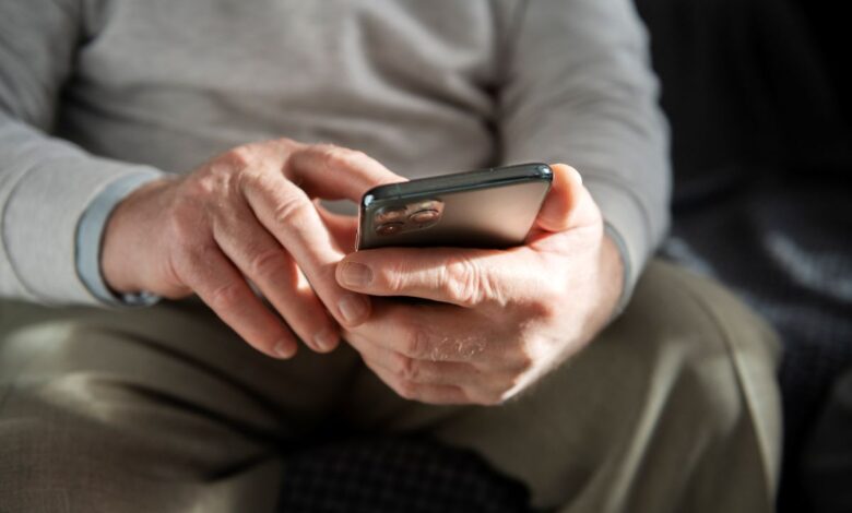 Mãos de idoso usando celular para aprender a fazer Pix