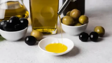 Azeite de oliva sendo servido em prato branco, com azeitonas verdes e pretas ao fundo, ilustrando marcas proibidas de azeite no mercado.