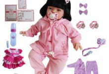 Boneca bebê reborn realista vestida de rosa com acessórios infantis ao redor