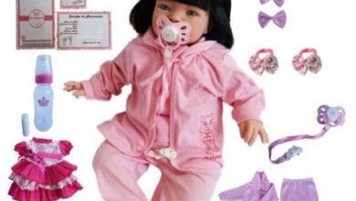 Boneca bebê reborn realista vestida de rosa com acessórios infantis ao redor