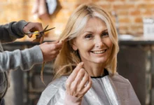 Mulher madura sorrindo enquanto recebe um corte de cabelo moderno em salão, valorizando a beleza natural aos 70 anos.