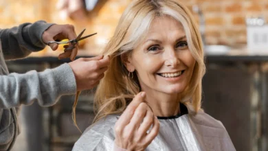 Mulher madura sorrindo enquanto recebe um corte de cabelo moderno em salão, valorizando a beleza natural aos 70 anos.