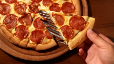 Pizza de pepperoni caseira sendo servida, com queijo derretido e crosta dourada.