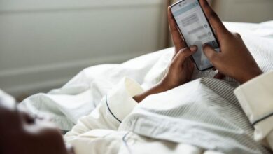 Pessoa deitada na cama enviando mensagem de boa noite pelo celular