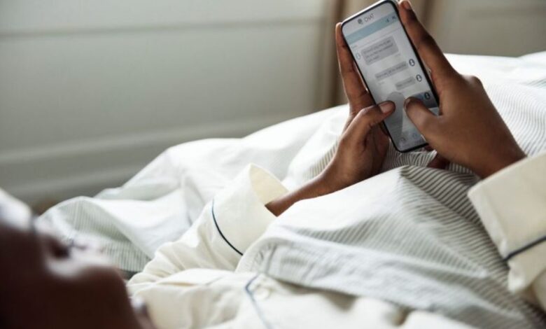 Pessoa deitada na cama enviando mensagem de boa noite pelo celular