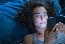 Pessoa sorrindo enquanto lê mensagem de boa noite no celular na cama