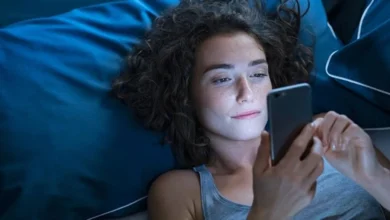 Pessoa sorrindo enquanto lê mensagem de boa noite no celular na cama