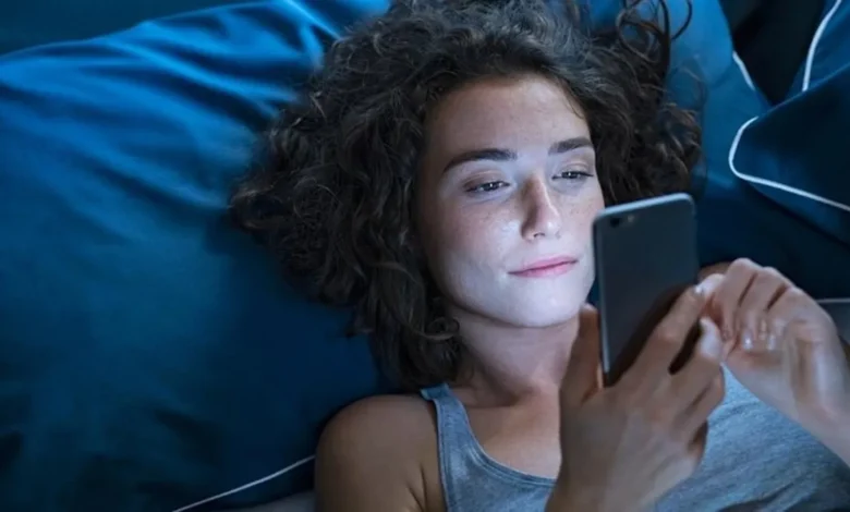 Pessoa sorrindo enquanto lê mensagem de boa noite no celular na cama