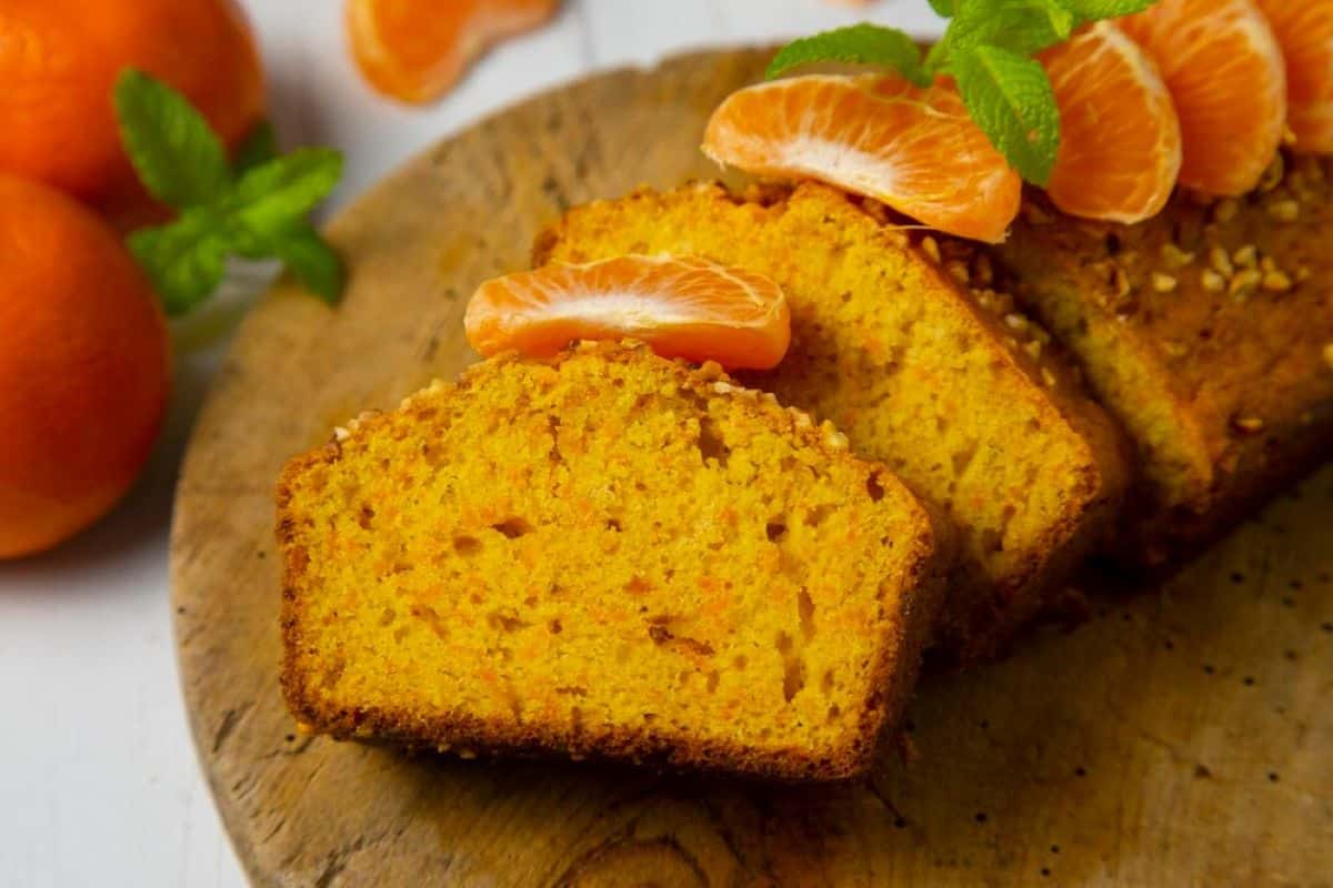 Fatias de bolo de fubá com laranja e pedaços de tangerina, decorado com folhas de hortelã.