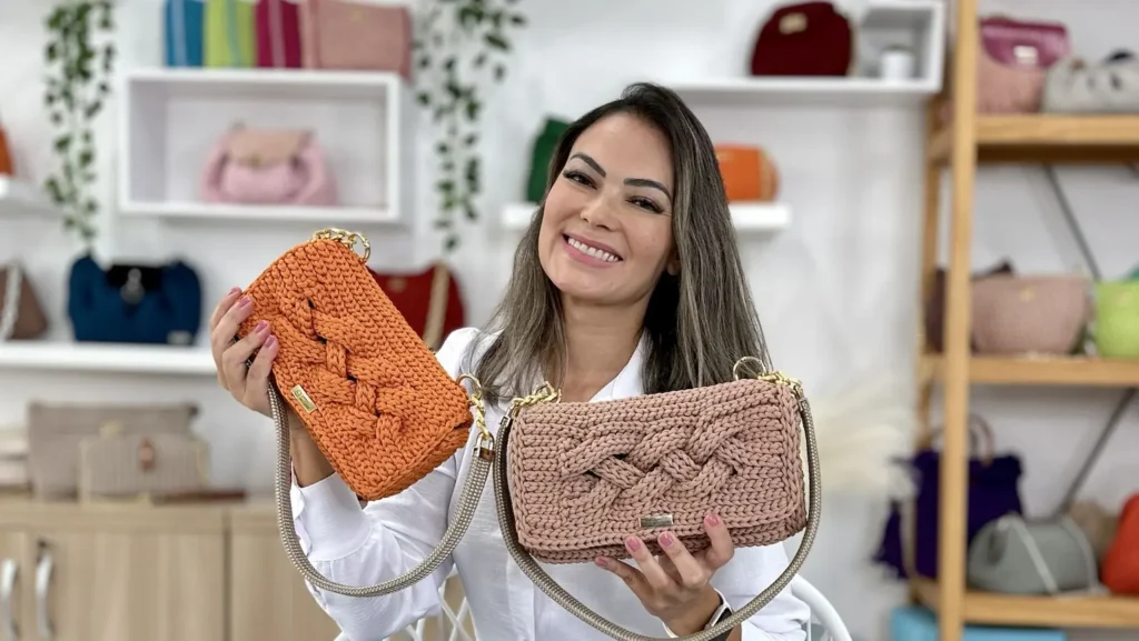Mulher sorridente segurando duas bolsas de crochê coloridas
