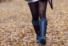 Mulher usando botas confortáveis no inverno enquanto caminha e usa o celular