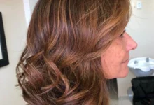 Cabelos iluminados em mulher madura com tons naturais de mel, caramelo e amêndoa, realçando a beleza aos 50+.