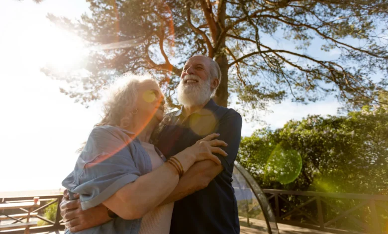 Casal idoso feliz abraçado ao ar livre, irradiando alegria e conexão emocional.