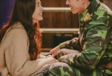 Casal protagonista do K-drama Pousando no Amor trocando sorrisos em um momento de carinho.