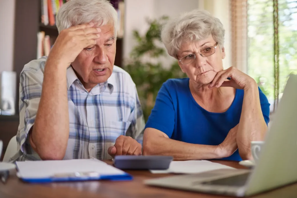 Casal de idosos preocupados analisando contas e usando calculadora para controle financeiro