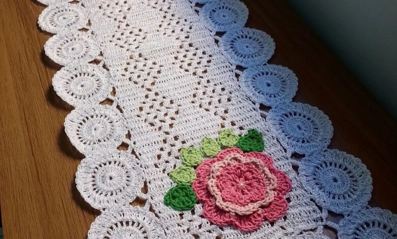 Caminho de mesa em crochê branco com flores rosas e detalhes em verde