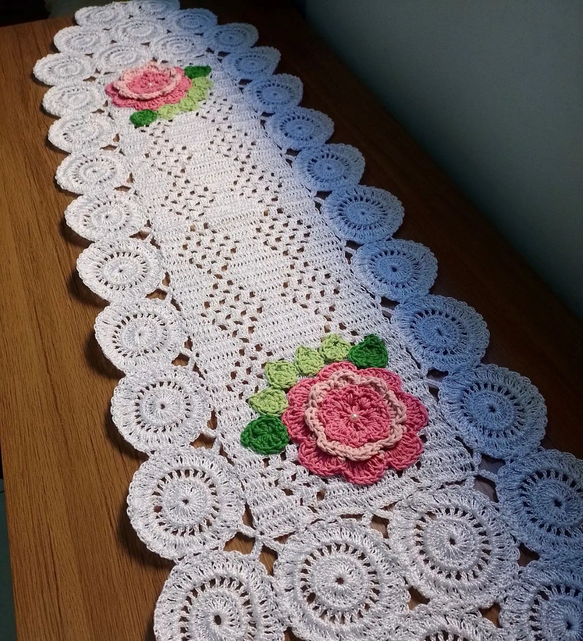 Caminho de mesa em crochê branco com flores rosas e detalhes em verde