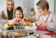 Criança, mãe e avó preparando uma receita juntas na cozinha, representando um momento especial para o Dia das Mães.