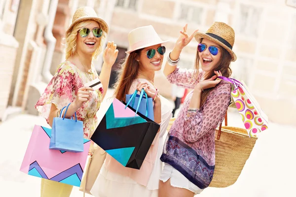  Grupo de amigas sorrindo e carregando sacolas de compras coloridas ao ar livre