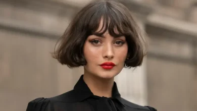 Mulher com corte bob moderno e franja, estilo tendência 2025, usando batom vermelho vibrante e blusa preta