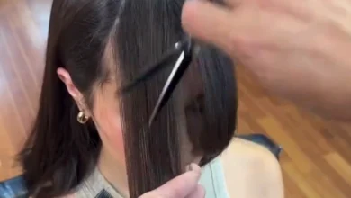 Mulher recebendo corte de cabelo Butterfly cut, com profissional aparando a franja cuidadosamente.