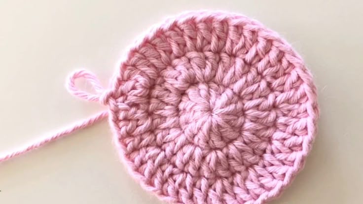 Peça de crochê circular em ponto alto feita com fio rosa claro, mostrando detalhes da trama apertada e formato levemente curvado