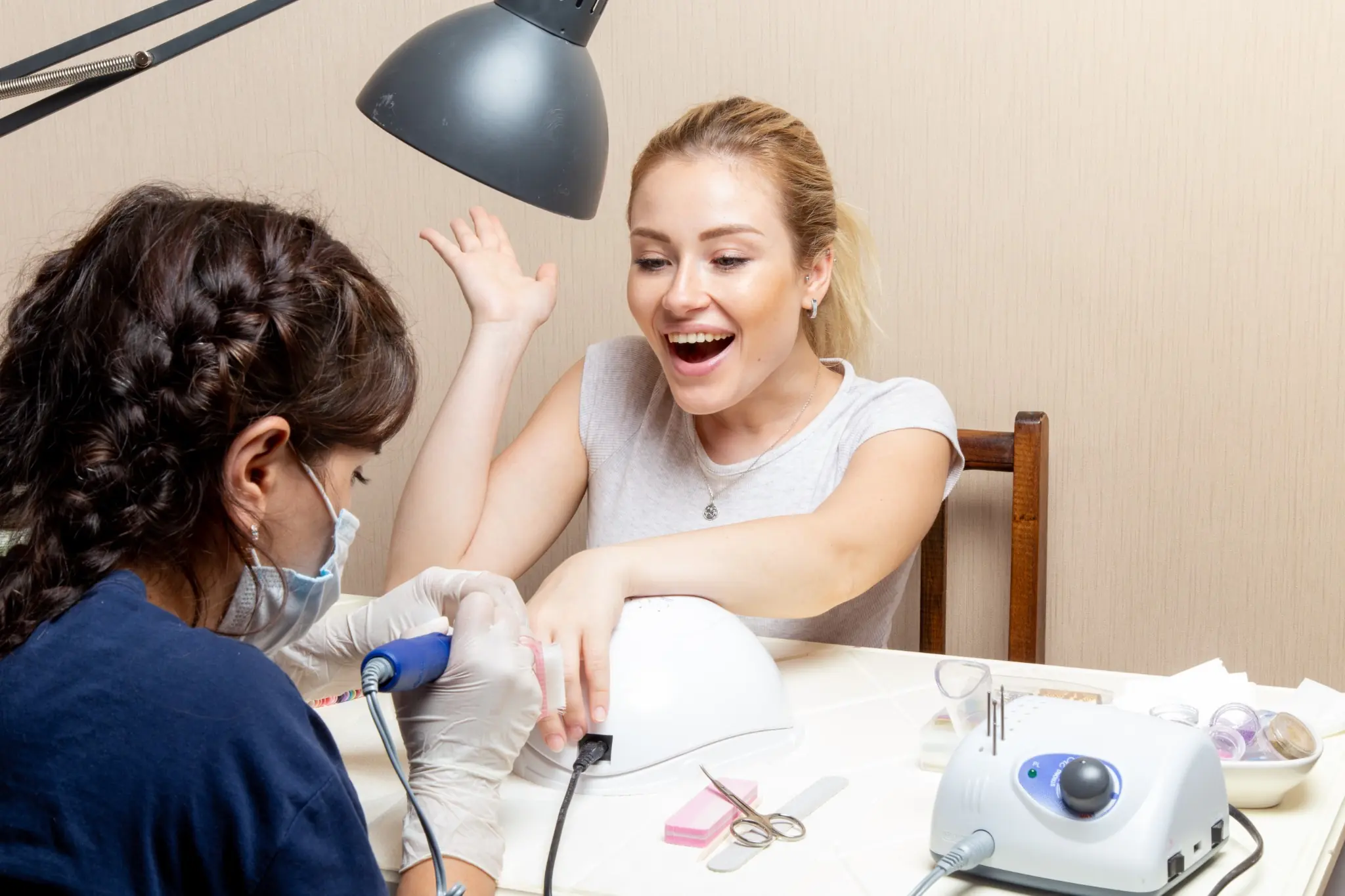 Cliente sorrindo enquanto faz manutenção de unhas postiças em salão de beleza.