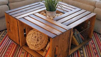 Mesa de centro feita com caixas de madeira recicladas, decorada com plantas e objetos criativos.