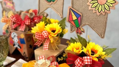 Decoração de mesa para festa de São João com arranjos de girassóis, bandeirinhas de juta, e detalhes em fita xadrez vermelho