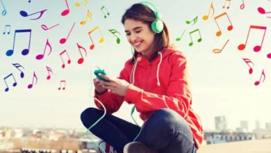 Jovem ouvindo música com fones de ouvido e sorrindo ao ar livre