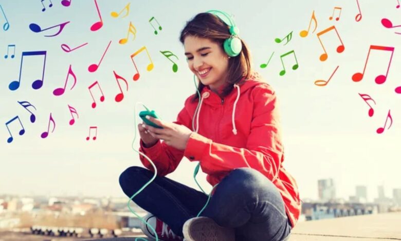 Jovem ouvindo música com fones de ouvido e sorrindo ao ar livre