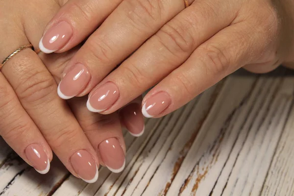 Unhas estilo francesinha em mãos femininas maduras com acabamento natural e elegante